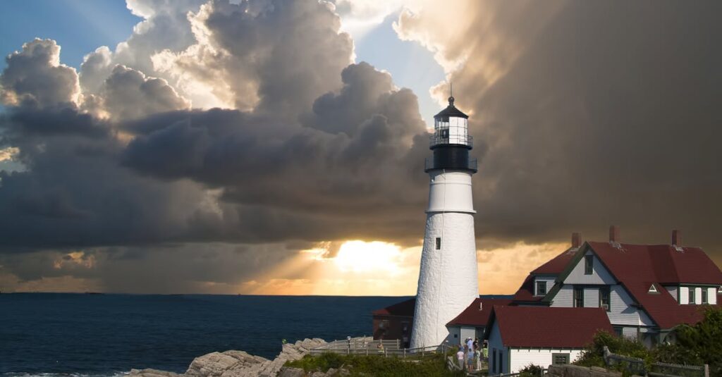 Breathtaking view of a lighthouse on a rocky coast with dramatic clouds and sunset.